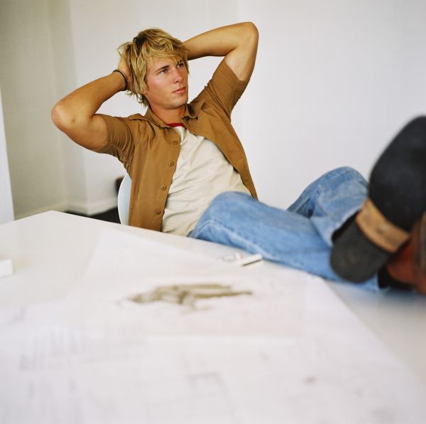 A Young Man Sitting An A Chair With His Feet Up On The Desk-w2