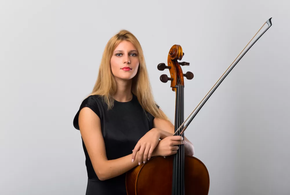young-blonde-girl-with-her-cello-posing-white-wall