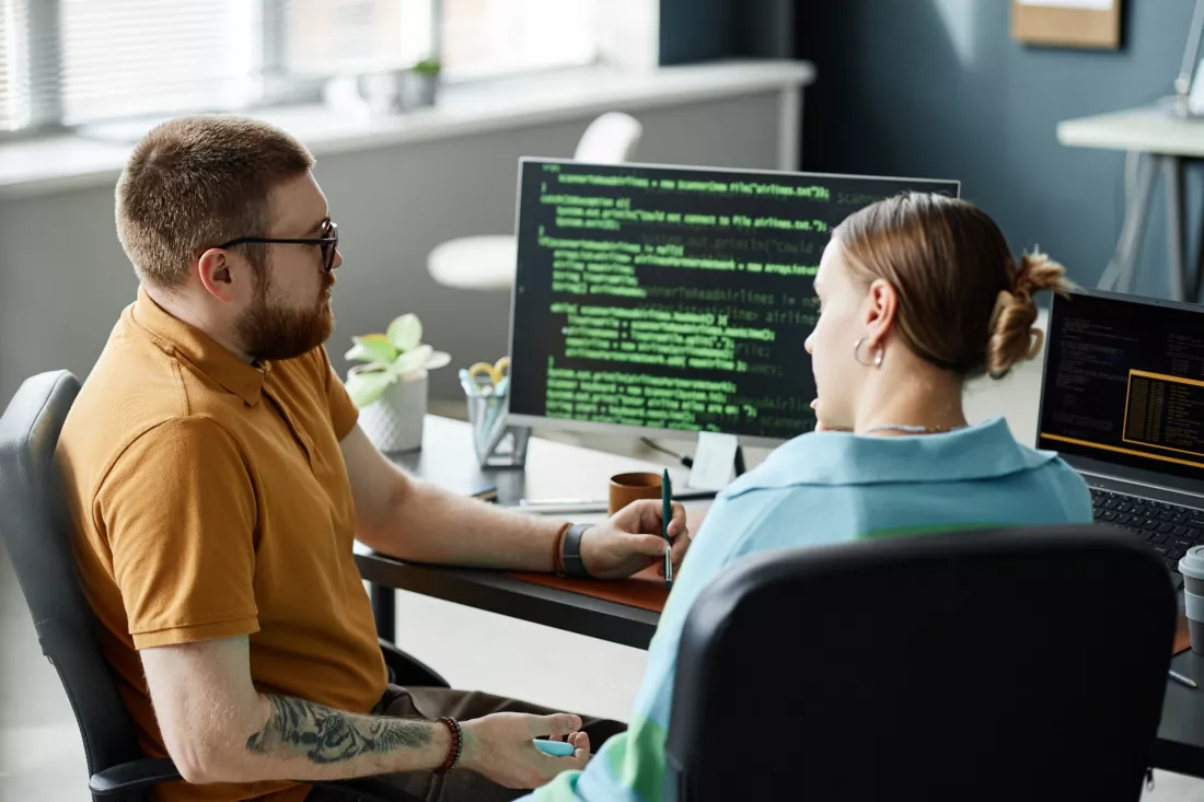 Programistka i programista pisza kod przy komputerze