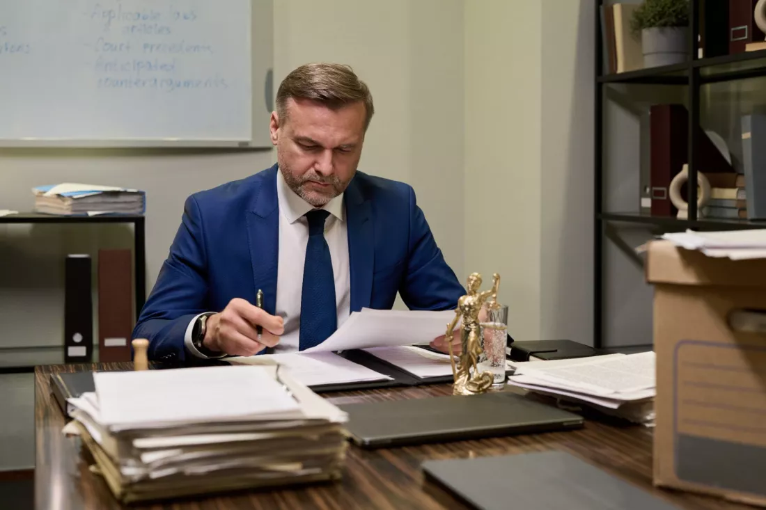 Radca prawny przeglada dokumenty przy biurku w kancelarii