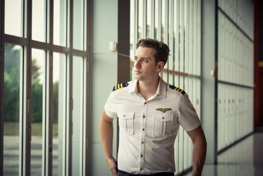 young-man-looking-away-while-standing-against-window