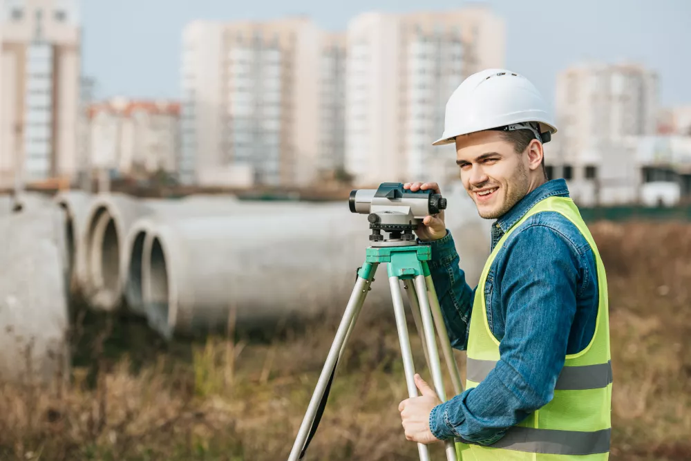 surveyor-with-digital-level-smiling-camera-with-building-materials-background