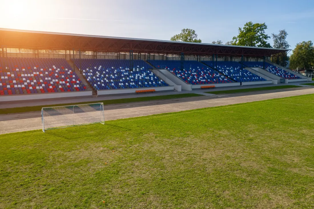 Pusty stadion piłkarski z trybunami w słoneczne popołudnie