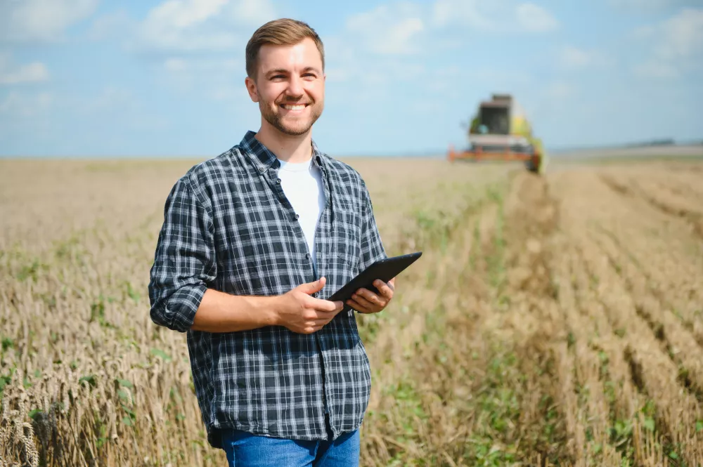 happy-farmer-proudly-standing-field-combine-harvester-driver-going-crop-rich-wheat-harvest-agronomist-wearing-flannel-shirt-looking-camera-farmland