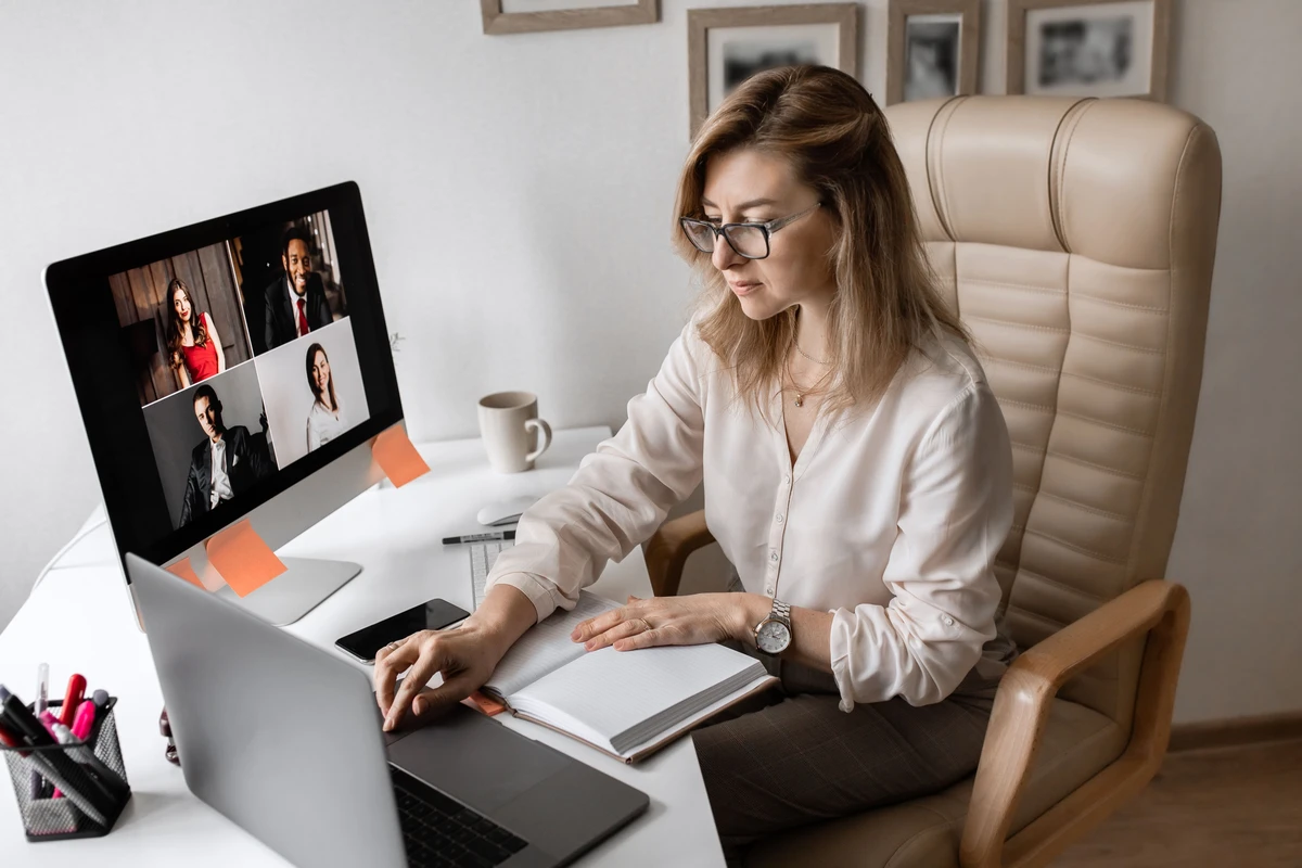 Młoda kobieta w okularach bierze udział w wideokonferencji na home office