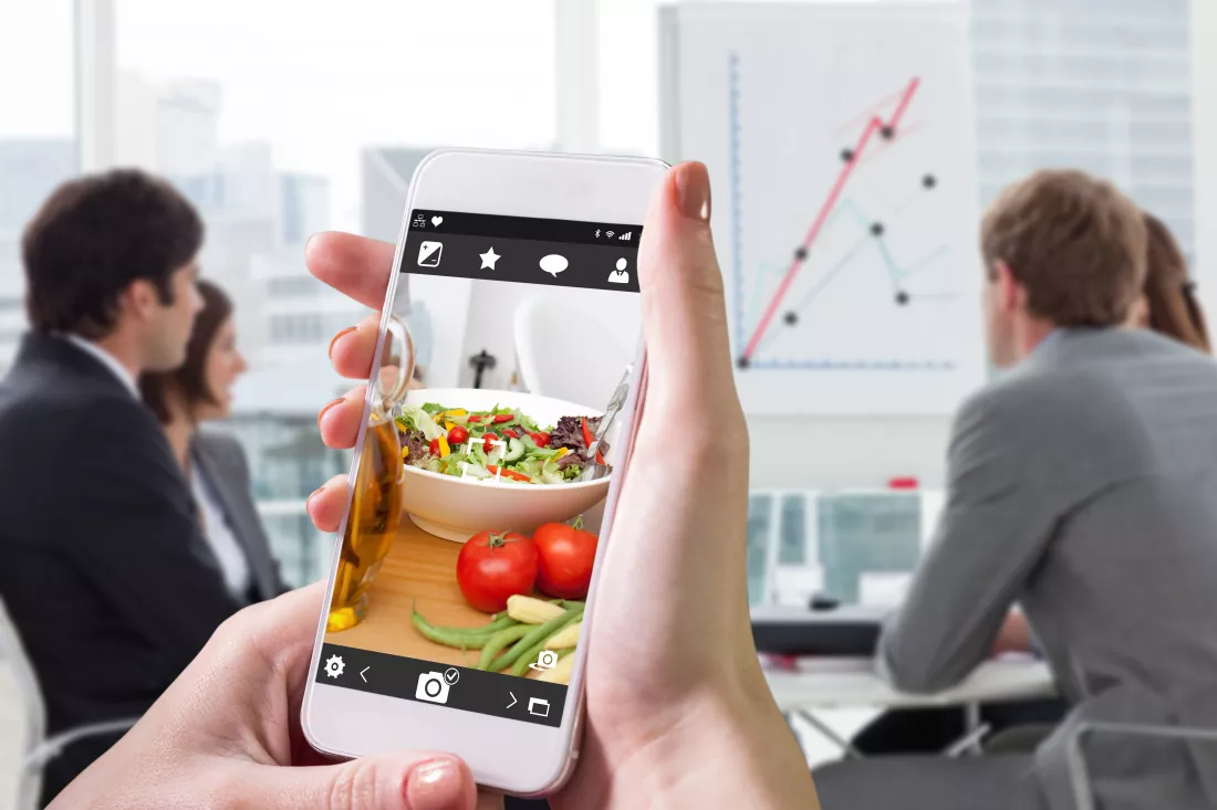 hand-holding-smartphone-against-close-up-salad